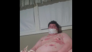 Fat male gagged with hand taped to leg masturbating