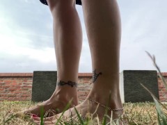 Slow motion milf barefoot in grass, wrinkled soles and red toes