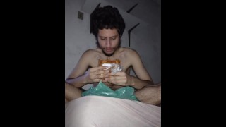 Homme avec un gros fétiche mangeant un chien chaud dans sa chambre