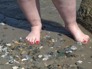 大きな足を持つ太った女性が岸に沿って歩きます。