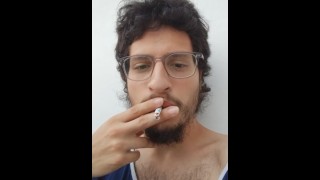 Fumando um único cigarrinho sentado em uma cadeira ao ar livre (fetiche)