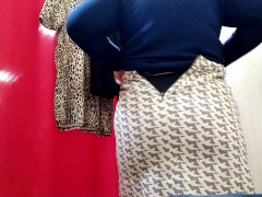 Curvy lady trying on clothes in a shopping mall fitting room