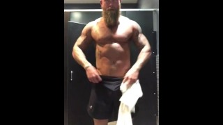 Fit tattooed man strips in gym locker room