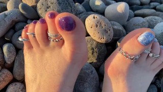 Hot e pés sensuais de Mistress Lara ao pôr do sol na praia pública