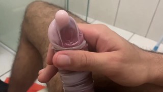 Masturbandosi giocando all'interno del preservativo pieno di balsamo in crema.
