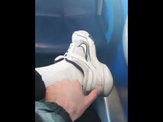 白い靴下とスニーカー。男は空の電車の中でジーンズを通してディックをけいれん