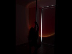 The gymnast dances at the pole arching very erotically.