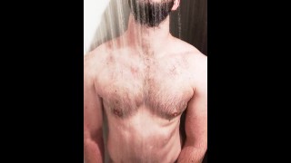 ひげを生やした筋肉のジョックはけいれんし、ジムのシャワーで濡れます