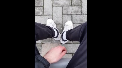 a guy in sneakers and white socks shows his feet at the train station