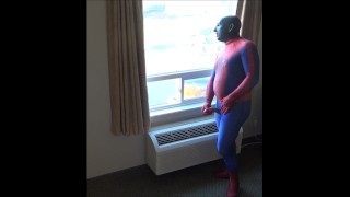 hombre araña en máscara de silicona black masturbándose en la ventana del hotel