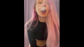 ピンクの髪の女の子が家でタバコを吸う