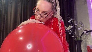 Chica looner con gafas y vestido rojo de PVC sopla un gran globo rojo y lo hace con el culo. DM para estar lleno