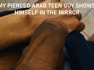 おなかのピアスアラブの十代の男は鏡の中で自分自身を披露