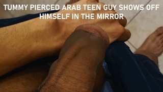 おなかのピアスアラブの十代の男は鏡の中で自分自身を披露