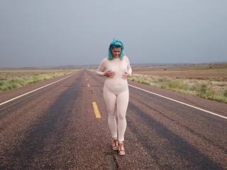 高速道路を歩く薄手のキャットスーツの熟女