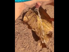 Girl Pissing on a large leaf that has fallen from a tree to the ground in Nature Park