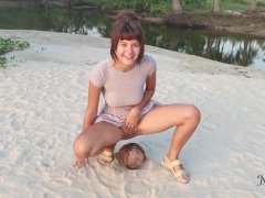 A shy girl squirts a small trickle of pee on a coconut