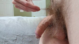 Haariger Kerl spielt mit seinem großen Schwanz auf der Bettkante