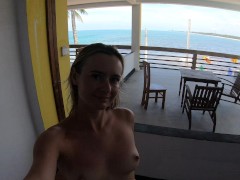 Naked girl walks on the balcony overlooking the ocean