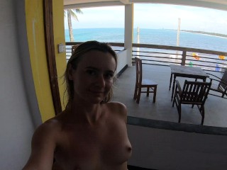 Naked girl walks on the balcony overlooking the ocean