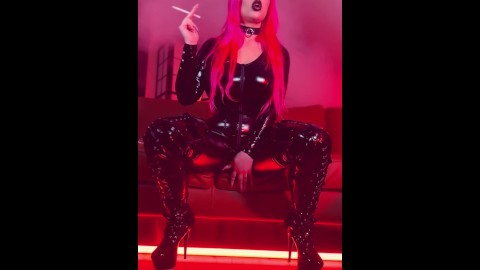 Pink haired Luvie Doll smoking EVE 120s cigarette in a PVC catsuit looking like the devil with nails