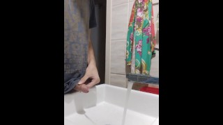 Fare pipì nel lavandino con l'acqua che scorre