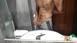 Atletische kerel masturbeert zijn grote lul in de badkamer
