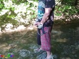 German guy stands in a creek, pisses and jerks off his hard cock