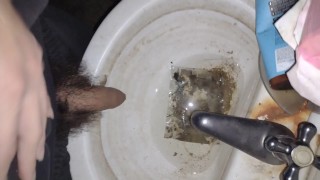 Homem peludo mijando na velha pia suja