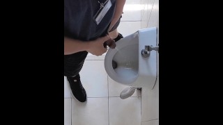 Paja arriesgada en el urinario público en el trabajo. Habitación del hombre