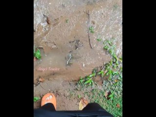 Girl pissing in a puddle in the pouring rain on the side of the road