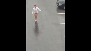 忙しい駐車場の戦利品で濡れた白いシャツで雨の中で踊る