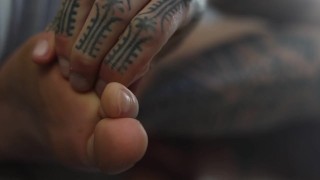 Adoración de pies con manos tatuadas