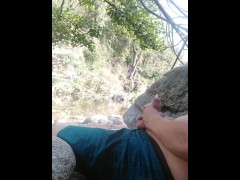 Boy playing with himself in a condom near a river