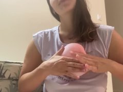 Woman plays with small pink balloon (the balloon doesn't burst)