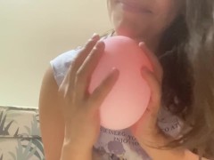Woman plays with small pink balloon (the balloon doesn't burst)