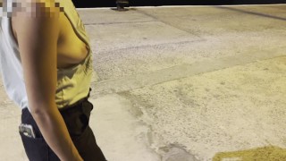 Nuit à pied au port de mer avec une chemise coupée de côté, montrant des seins et des mamelons en public autour des gens