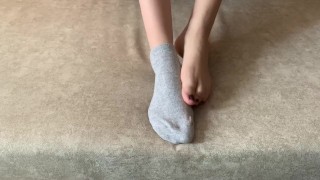 Het meisje streelt haar benen en trekt haar sokken uit met haar voeten