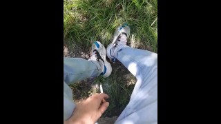 Jonge kerel in sneakers en blauwe jeans rookt in het bos