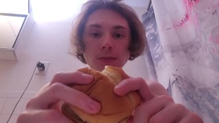 Голая телочка ест гамбургер, находясь в туалете