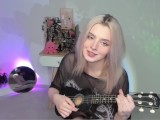 Hot blonde girl playing on ukulele and singing in naughty outfit