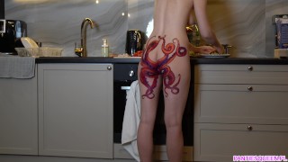 Naakte huisvrouw met octopus-tatoeage op kont kookt diner