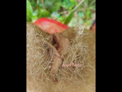 Village woman in a red tunic is pissing in the middle of a green field