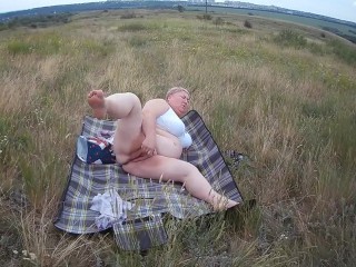 fat woman masturbates with a toy in the field