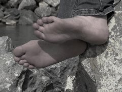 Feet of a mature woman on the river bank.