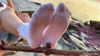 Goddess feet in dirty white socks closeup against sea sunset