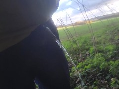 Pissing outside near main road beautiful field