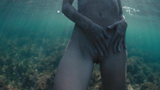 A naked buttty girl swims in the ocean, but someone is watching her