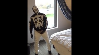 skeletmasker in panty en spijkerbroek bij het raam van het hotel