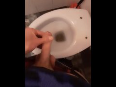 A young skater pisses in the toilet of a bar